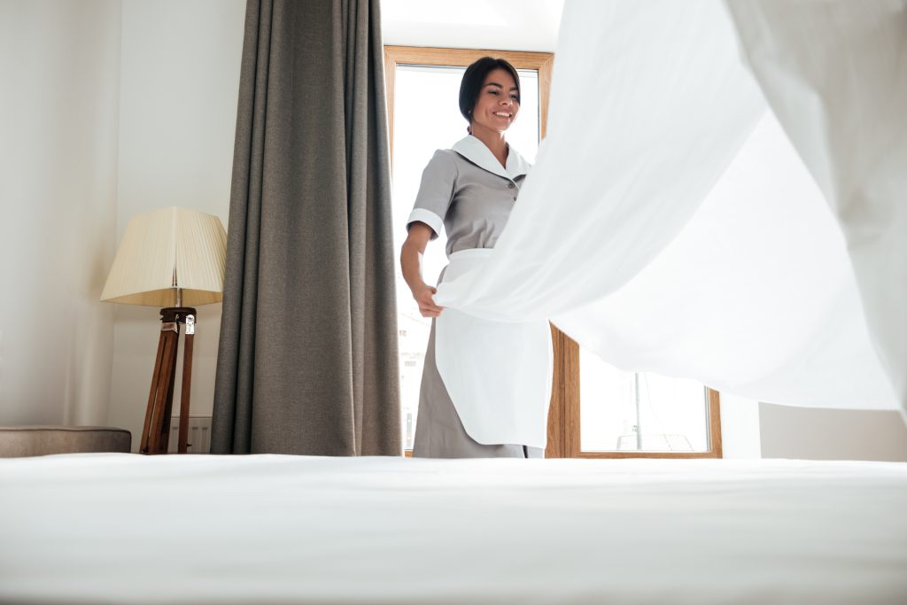 Hotel maid changing bed sheets